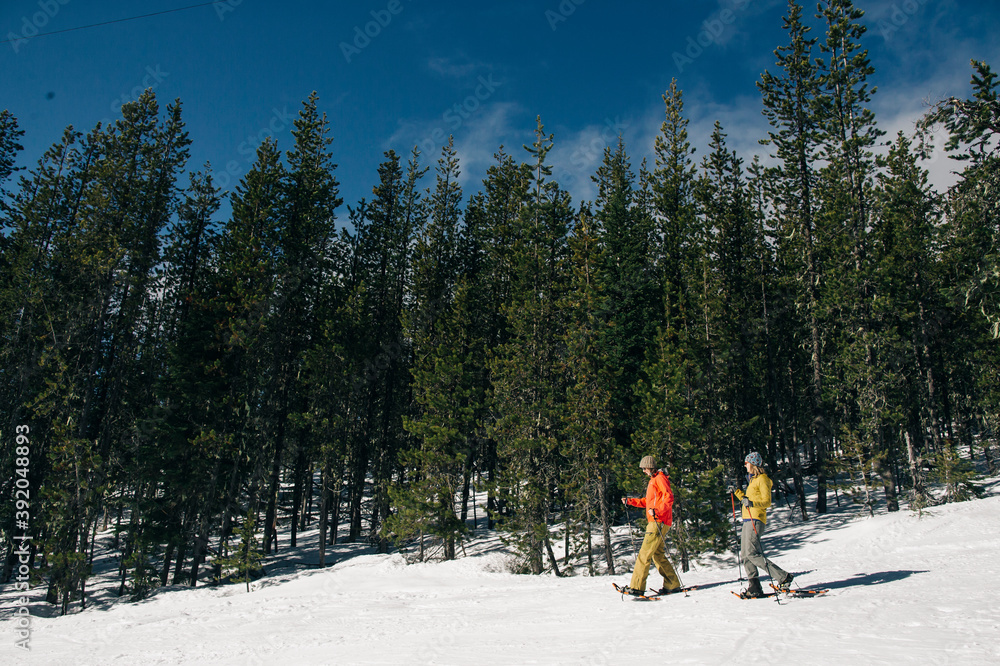 Two young women snowshoe on Mt. Hood on a sunny day. Two young women snowshoe on Mt. Hood on a sunny day.