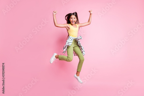 Full size photo of trendy stylish astonished brown haired girl jump wear yellow singlet green pants isolated on bright pink background