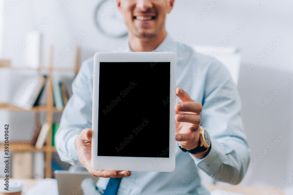 Cropped view of digital tablet with blank screen in hands of smiling businessman on blurred background Cropped view of digital tablet with blank screen in hands of smiling businessman on blurred background