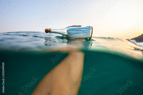 Holding a Covid-19 surgical face mask inside a glass bottle in the sea photo