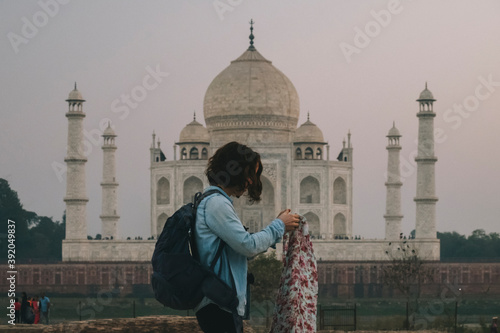 Young woman backpacker dressing her Pashmina before leaving Mehtab Bagh, with Taj Mahal in the background. photo
