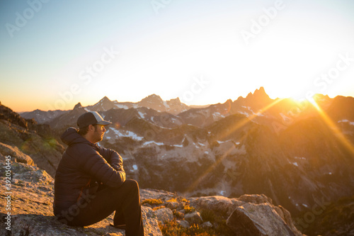 Side view of mountaineer watching sunset from high mountain pass. photo