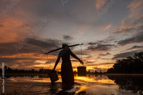 SRA SRANG,ANGKOR PARK, SIEM REAP, CAMBODIA - 11 August 2013: Local lady collects water in buckets over the shoulder for her garden from angkorian bathing pool.