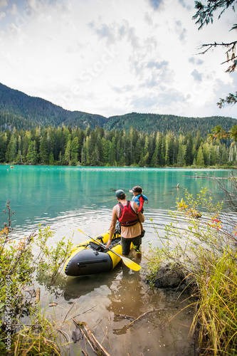 Dad lifts son into inflatable boat in a mountain lake outdoor setting photo