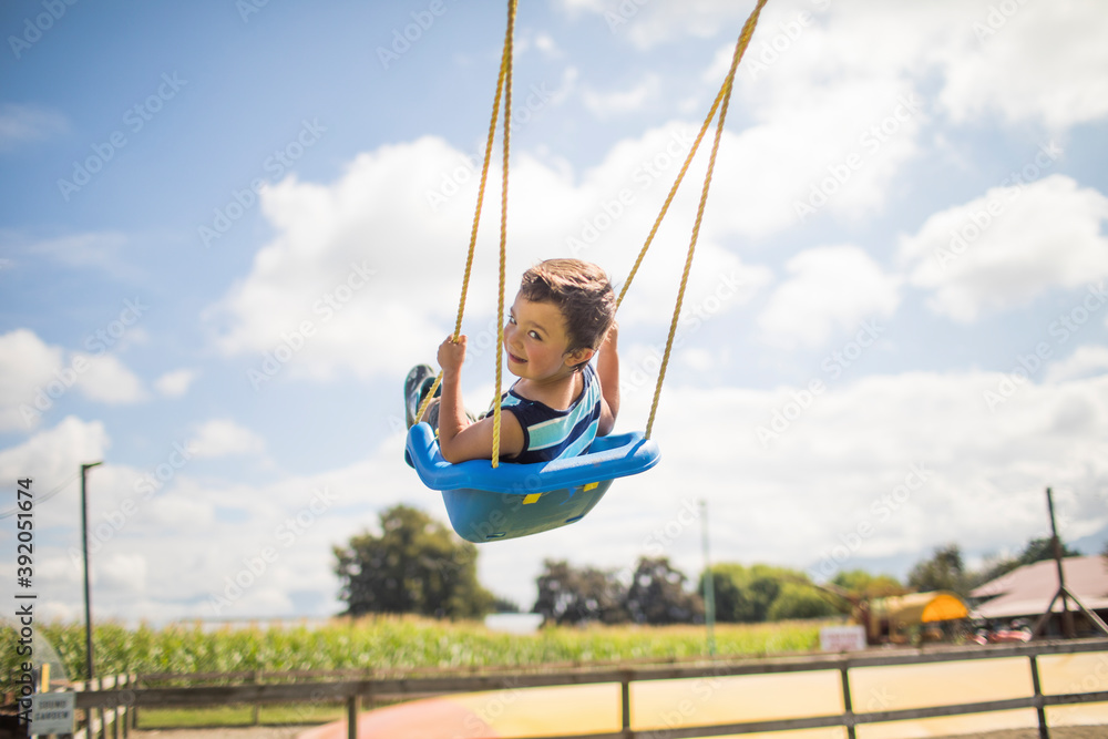 Low angle view of boy swinging outdoors. Low angle view of boy swinging outdoors.