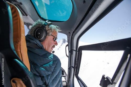 Helicopter pilot looks for a place to land in snow covered mounatins.
