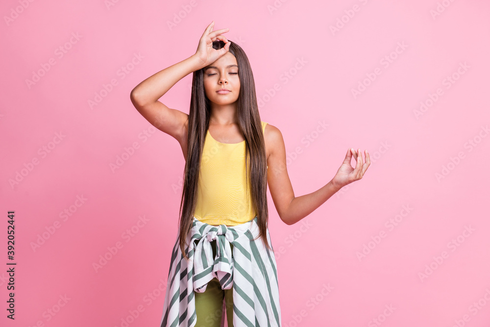 Photo of concentrated girl make om sign hand on head wear yellow singlet isolated on pink color background Photo of concentrated girl make om sign hand on head wear yellow singlet isolated on pink color background