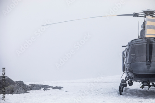 Helicopter landed on snow covered mountain summit. photo