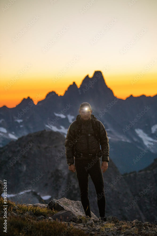 Backpacker hikes with headlamp on at dusk. Backpacker hikes with headlamp on at dusk.