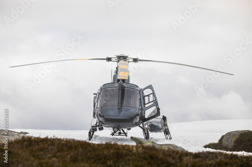 Helicopter landed on snowy mountain ridge.