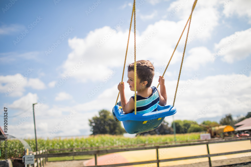 Low angle view of boy swinging outdoors on blue swing at playground. Low angle view of boy swinging outdoors on blue swing at playground.
