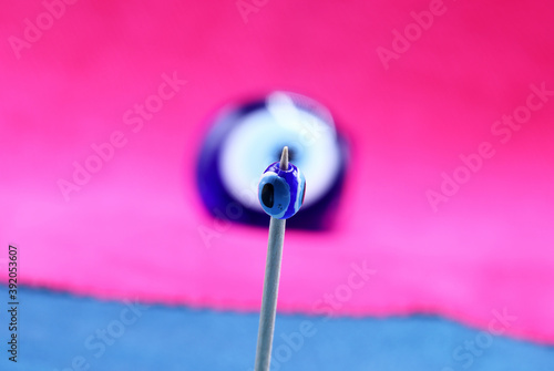 blue evil eye bead on a pink background © aykutkarahan