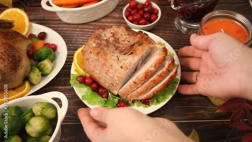 Woman hand put on the table traditional sliced honey glazed ham for festive Christmas or Thanksgiving day.