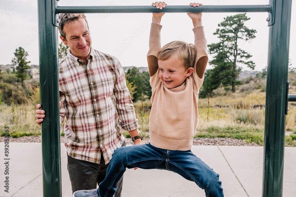 Young boy hanging on a bar at a park outside Stock Photo Adobe Stock