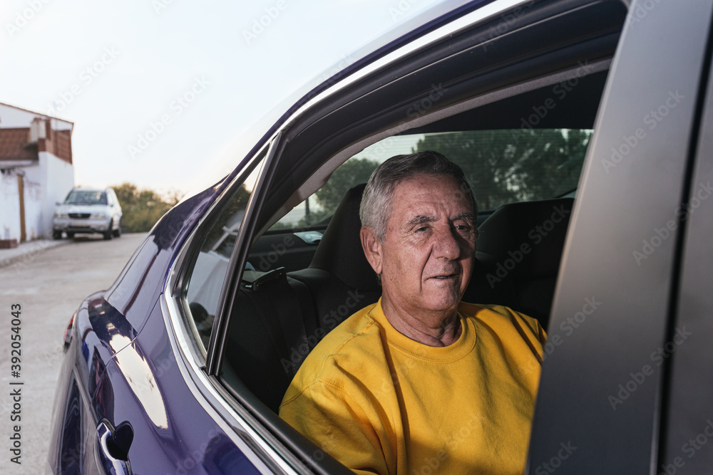 An old man sitting in the back seat of an electric car An old man sitting in the back seat of an electric car