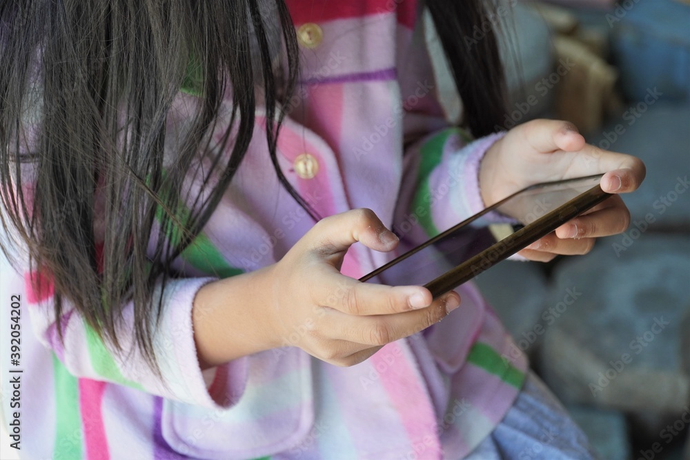 Little child girl is playing game on mobile phone.