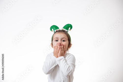 A girl with a hoop in the form of an elf hat on her head sends an air kiss. Christmas concept.