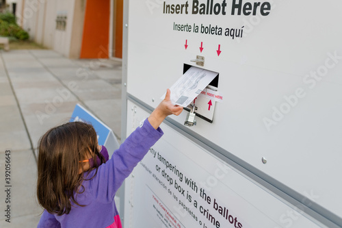 Little girl placing ballot in a drop box for absentee voting