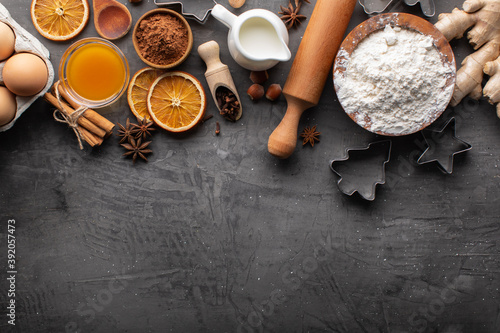 Fresh and healthy ingredients for gingerbread cookies on a dark textured background. Cooking dough for gingerbread cookies. Christmas background for baking, top-down view, copy space.