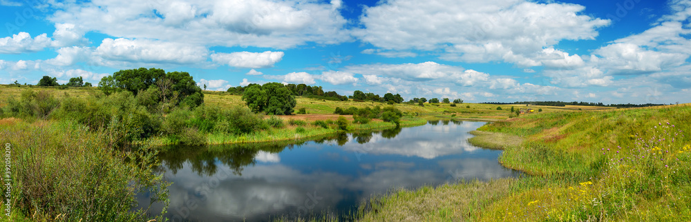 Beautiful landscape with calm river and green hills with trees at sunny summer day.