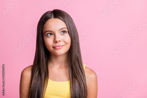 Photo portrait of dreamy kid looking at blank space isolated on pastel pink colored background