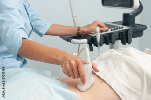 The doctor makes an ultrasound examination of the girl's internal organs. The doctor runs the sensor along the back