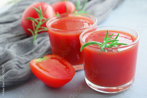 Tomato juice in a glass glass and fresh tomato on a wooden background.