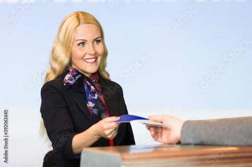 Friendly hostess giving passport to passenger