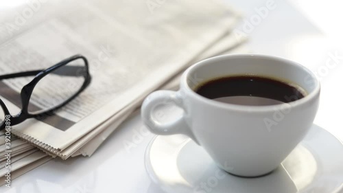 Newspapers and coffee cup, with reading glasses.