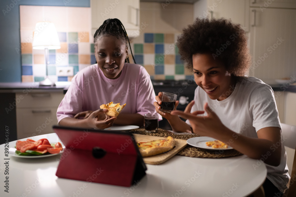 Laughing ladies having online call while dining at evening Laughing ladies having online call while dining at evening