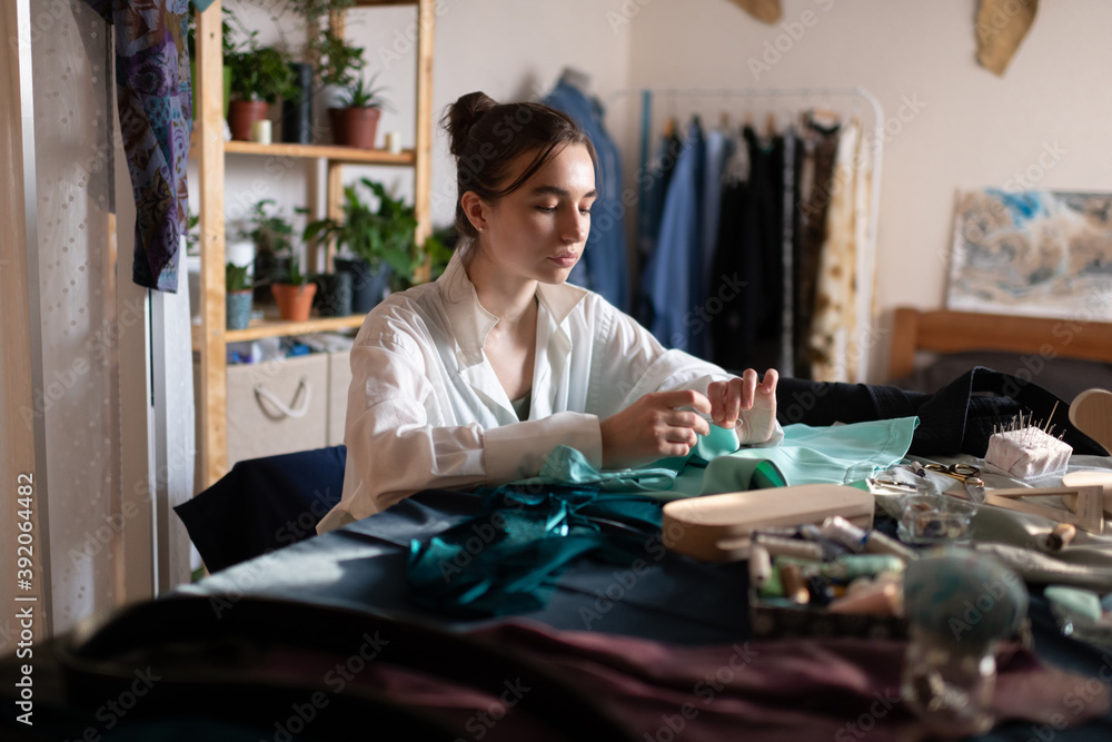 Calm seamstress woman sewing in home workshop Calm seamstress woman sewing in home workshop