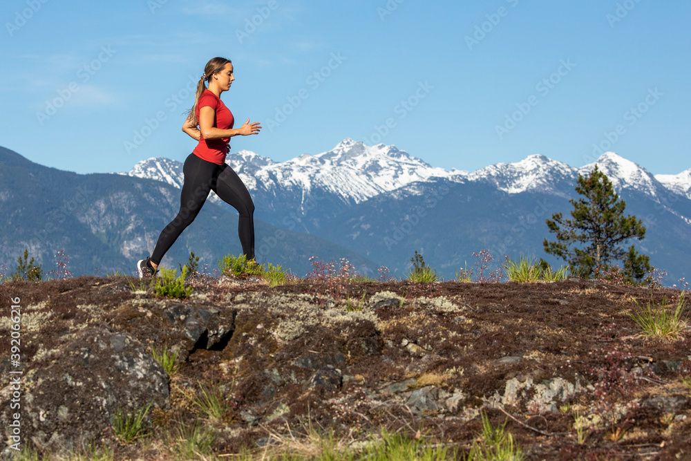 Side view of strong sportswoman running against snowy mountain ridge during fitness workout in countryside Side view of strong sportswoman running against snowy mountain ridge during fitness workout in countryside