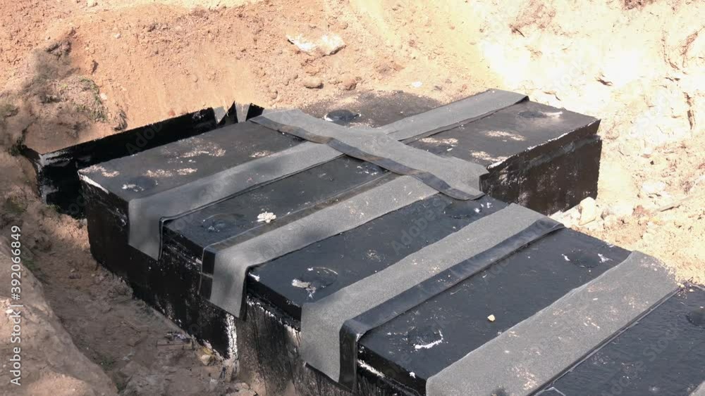 Frame for connecting pipes in the trench of sand. Painting bitumen at