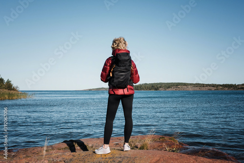 woman staning on a rock with a backpack looking at the ocean & islands photo