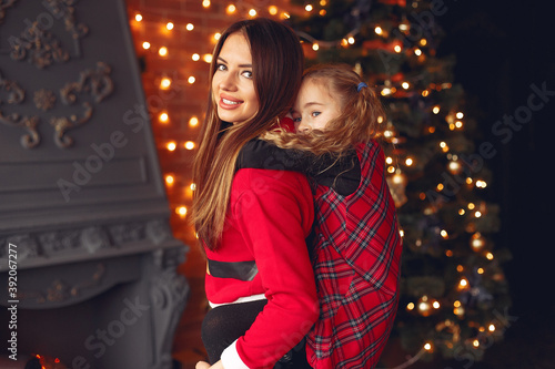 Beautiful mother in a santa's costume. Family with cristmas gifts. Girls near fireplace.