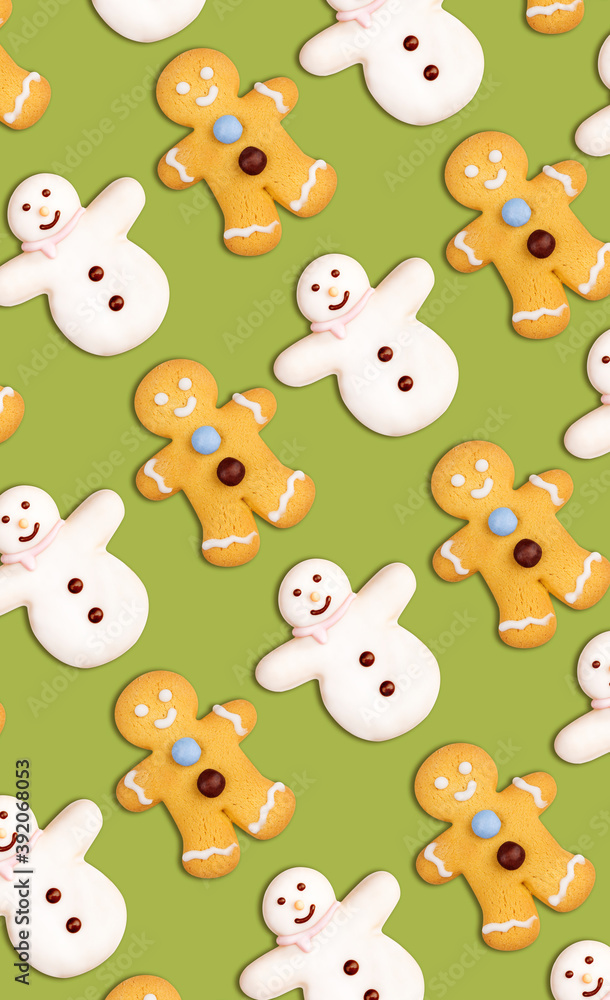 Obraz premium Vertical christmas cookies pattern in the shape of a snowman and a gingerbread man decorated with icing sugar and fondant on a green background