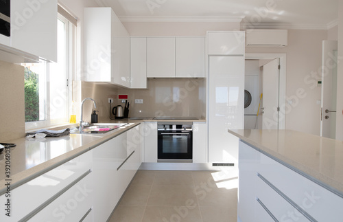Brand new modern kitchen with white cabinets and beige stone counter top and ceramic tiled floor