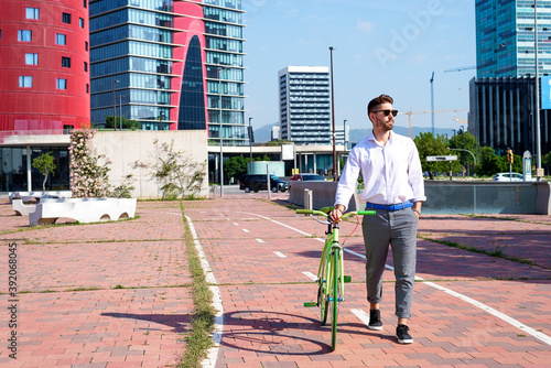 Bearded man in sunglasses walking with bike by bicycle track outdoors photo