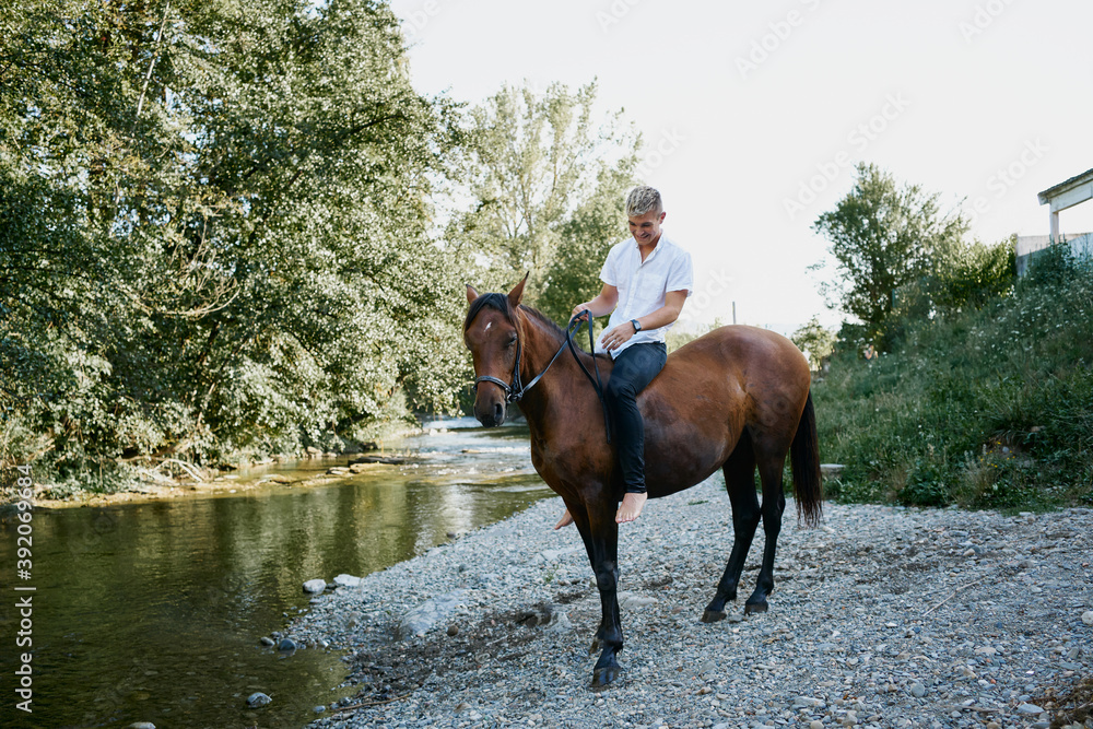 Portrait of a young blond man riding a horse over a river Portrait of a young blond man riding a horse over a river