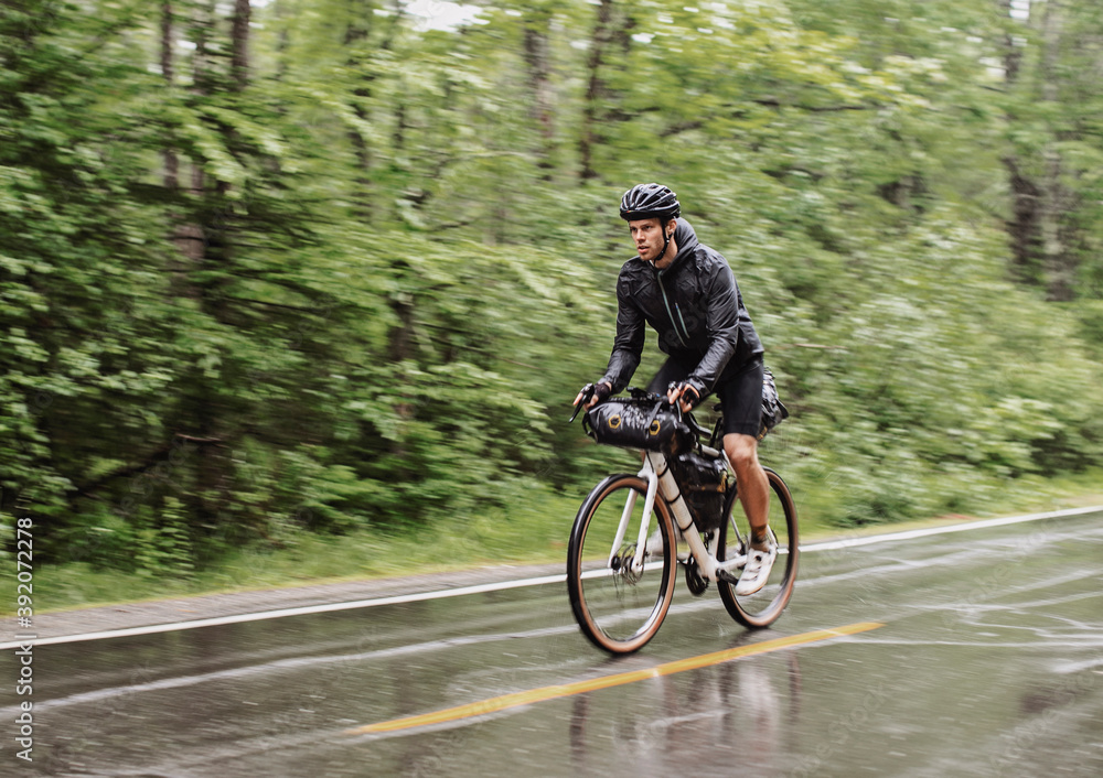 wet and soaked cyclist rides in pouring rain on road in Boothbay Maine wet and soaked cyclist rides in pouring rain on road in Boothbay Maine