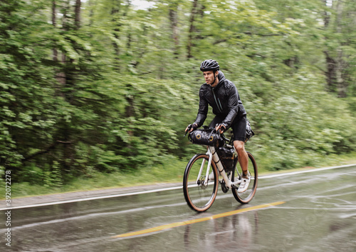 wet and soaked cyclist rides in pouring rain on road in Boothbay Maine