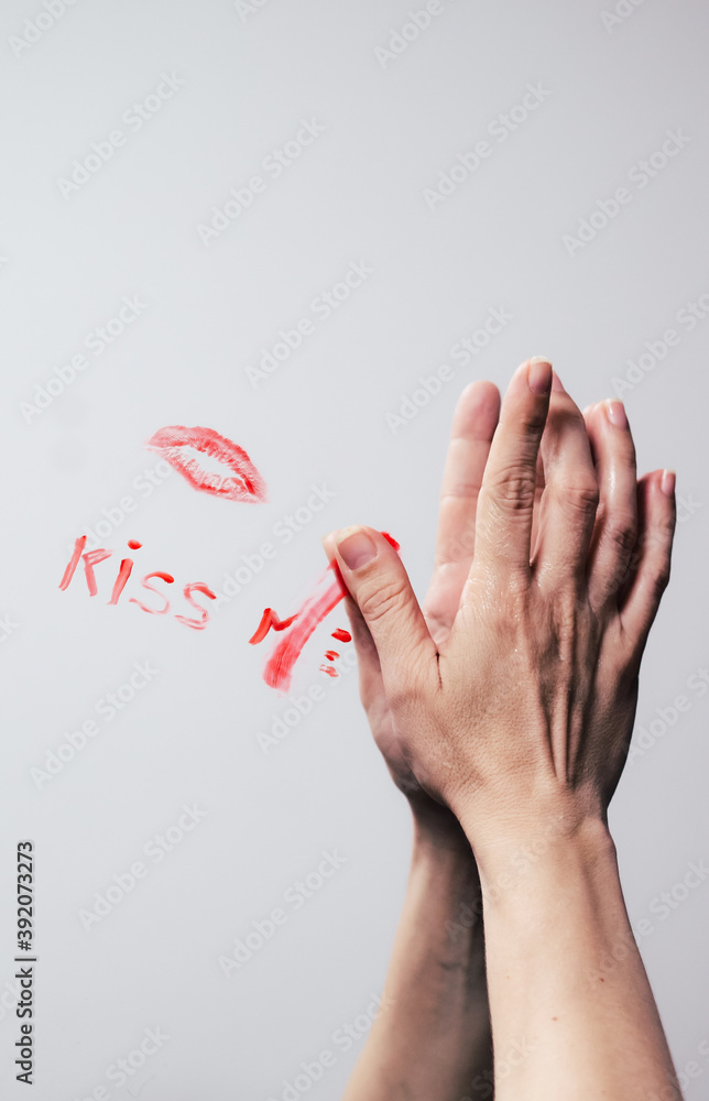 Hand erasing the phrase kiss me made with lipstick on a mirror