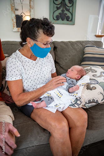 Woman wearing face mask holding newborn baby. photo