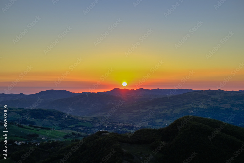 Red sun rising over the colorful sky and mountains landscape. Sunrise in mountains, Natural background. Italian Apennine