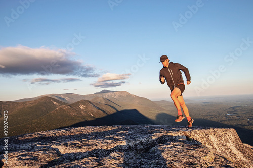 fit male trail runner runs across rocks on summit of Doubletop, Maine photo