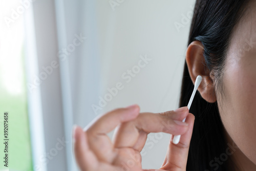 woman cleaning ear with cotton swab. Healthcare and ear cleaning