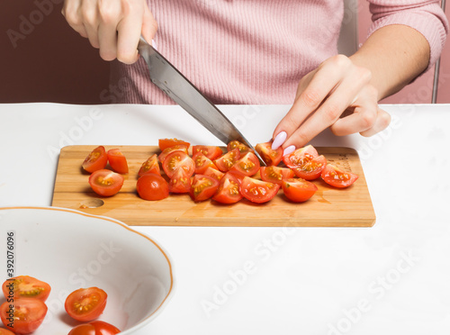 a woman was slicing cherry tomatoes on a chopping Board