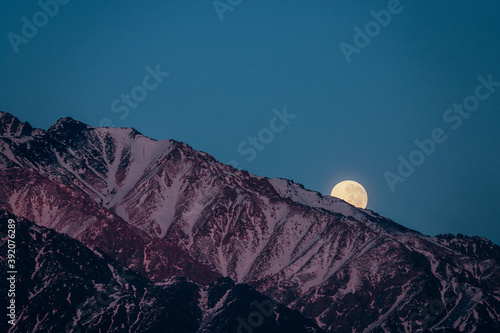 full moon hiding behind the andes mountain range in mendoza argentina photo