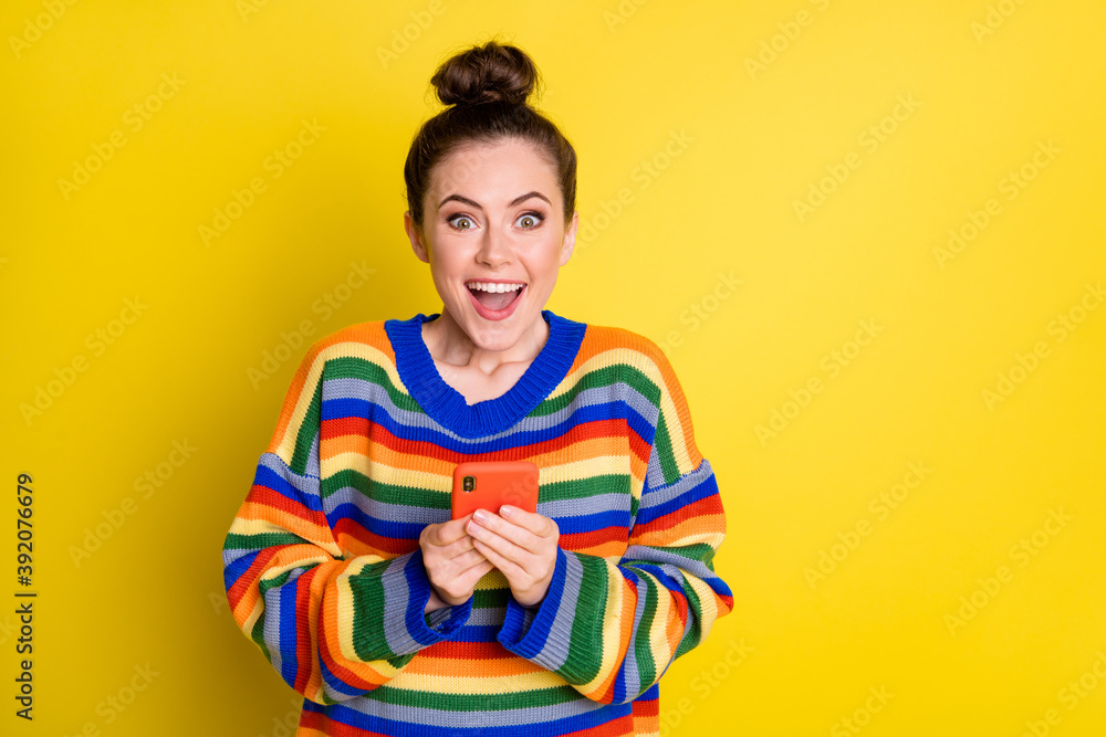 Photo of impressed funny brunette girl hold telephone wear rainbow sweater isolated on bright yellow color background