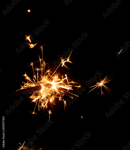 Burning sparkler against black background